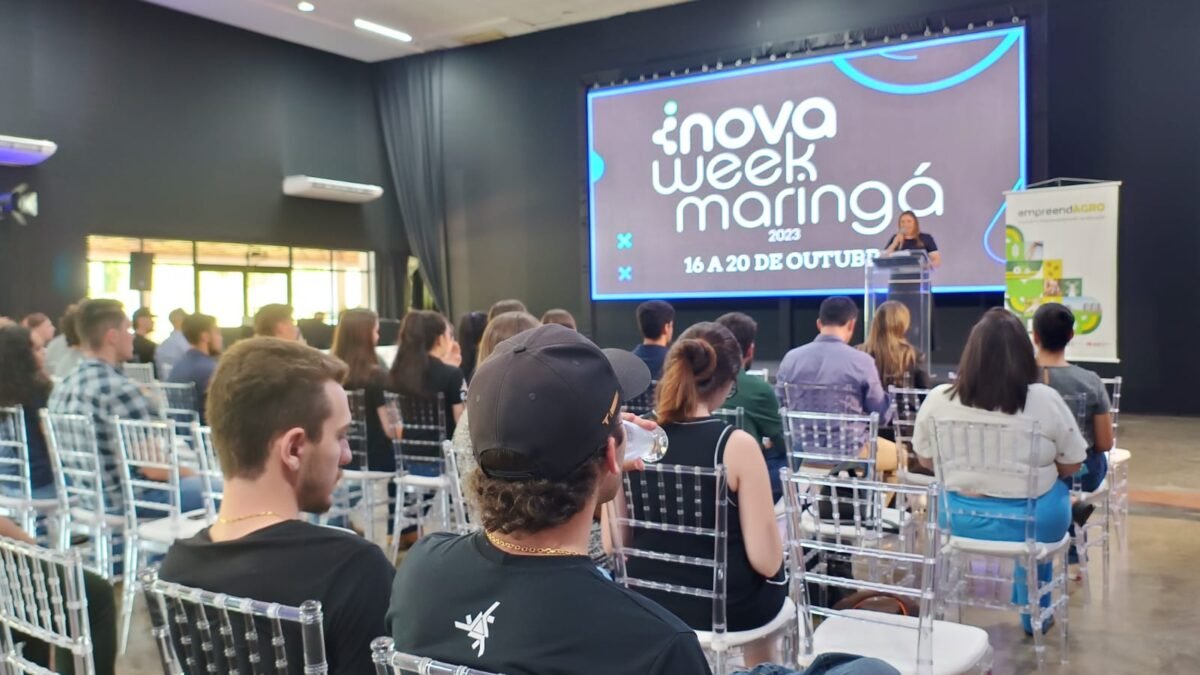 Público na InovaWeek Maringá, em auditório com palco e tela do evento.